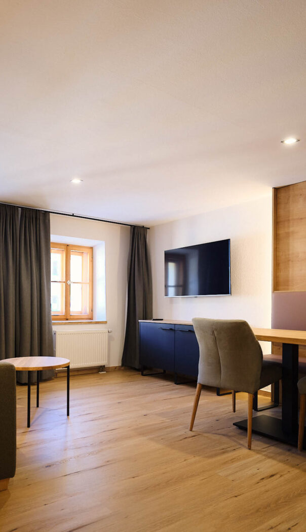 Ansicht des Wohnzimmers mit Tisch, Fernseher und Sofa